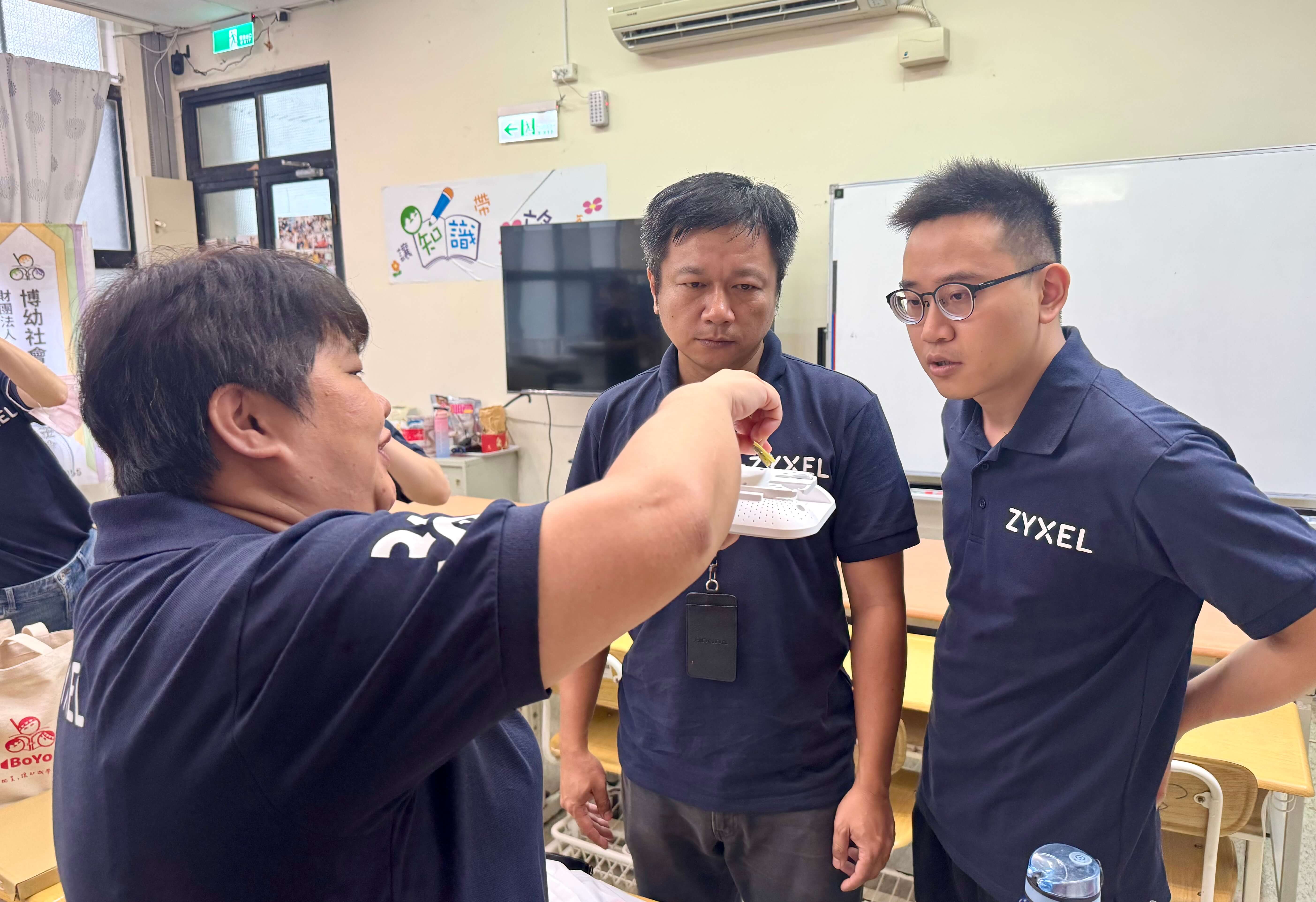 Zyxel Networks volunteers in blue shirts gather around a table to install equipment at Boyo Social Welfare Foundation's Jianshi branch.