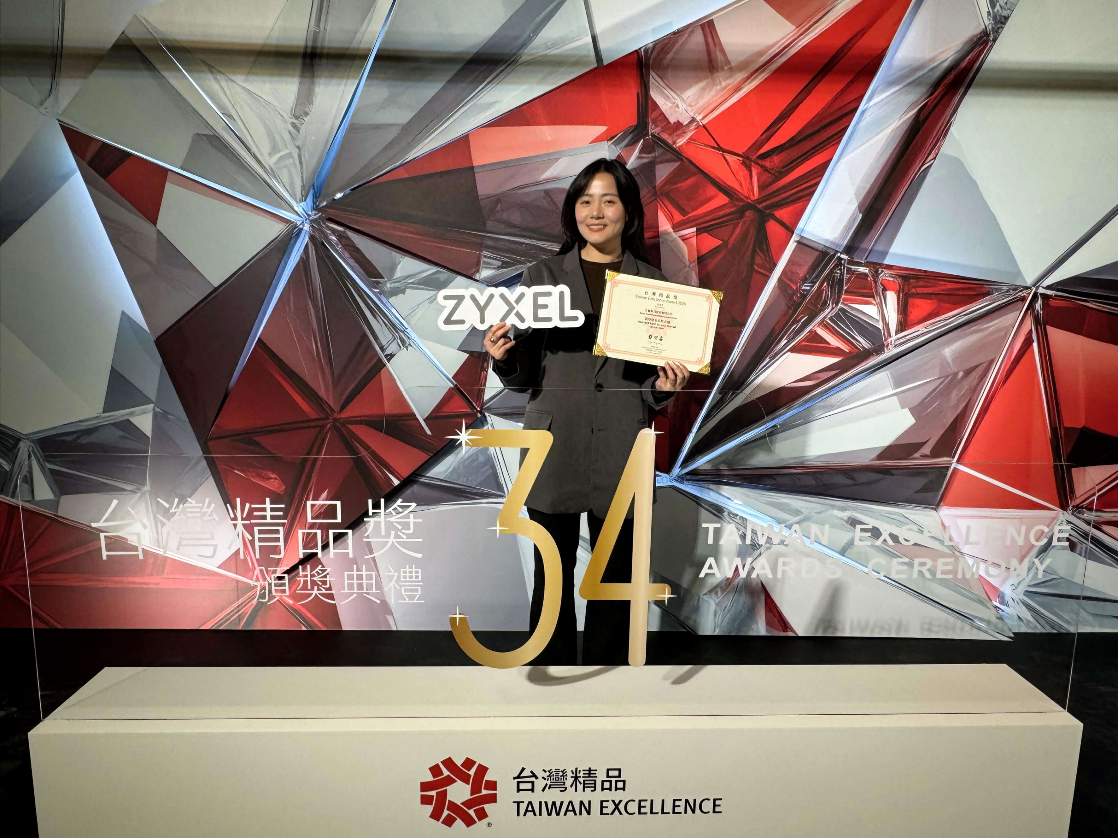 Avani Chen, Product Marketing Manager at Zyxel Networks, holds an award plaque in front of a large display.