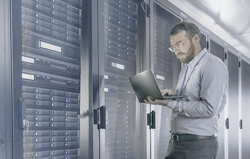 An IT professional uses a laptop to manage network servers, representing Zyxel's Nebula secure cloud management case study