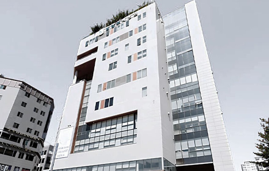 A tall, modern white hospital building with orange accents and large glass windows under a clear blue sky in Namyangju.
