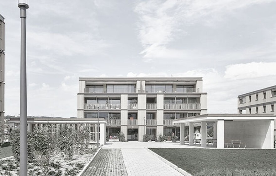 Rütipark in Switzerland with many balconies, landscaped courtyard, pathways, and open communal structures under cloudy sky.