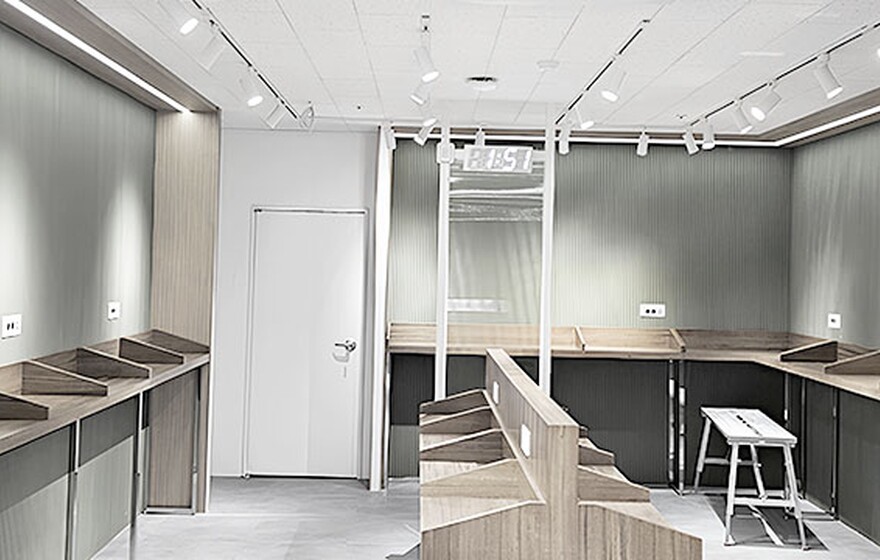 Modern study area with wooden carrel desks against olive green corrugated walls under bright track lighting.