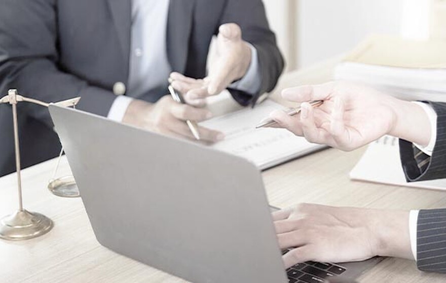Case study: Lawyers at a desk with a laptop and scales of justice, featuring Zyxel Networks Nebula solution for a law firm.