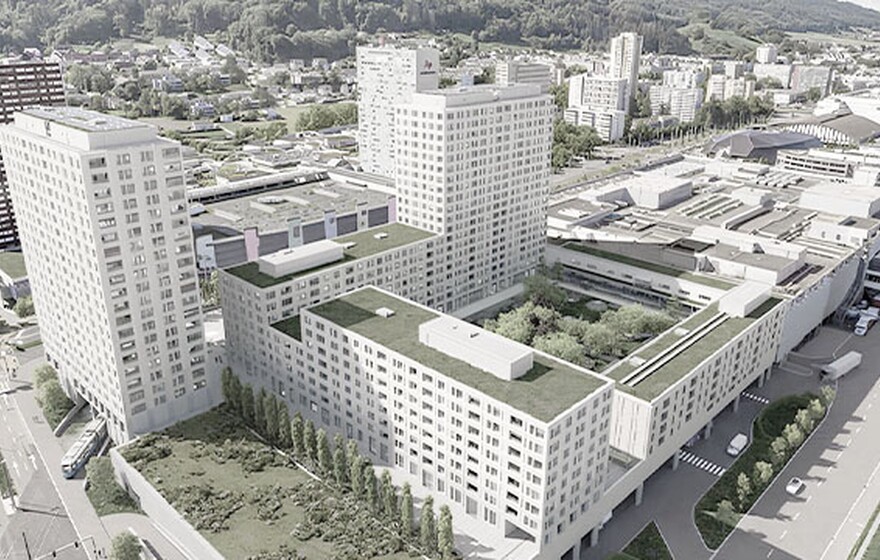 Aerial view of a modern multi-building apartment complex in Switzerland with green rooftop gardens in an urban landscape.