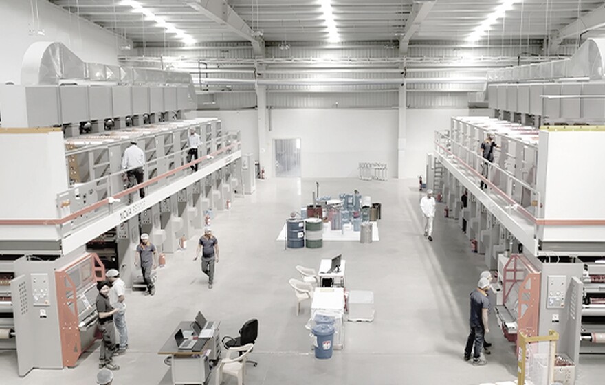 Workers operate large-scale printing and packaging machines inside a modern India Printing & Packaging factory  