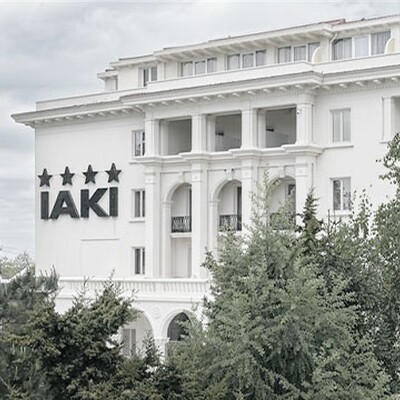 IAKI Conference & Spa Hotel exterior view with classic architecture and four-star sign, surrounded by lush green trees in Mamaia.