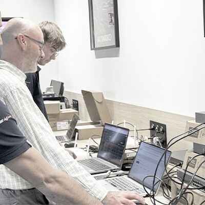 Nebula MSP Pack case study. IT staff configure Zyxel Ethernet switches and laptops in a workspace with monitoring screens.