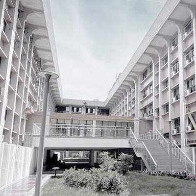 Providence University academic building featuring a modern sky bridge and lush greenery under a bright, clear blue sky.