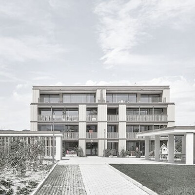 Rütipark in Switzerland with many balconies, landscaped courtyard, pathways, and open communal structures under cloudy sky.