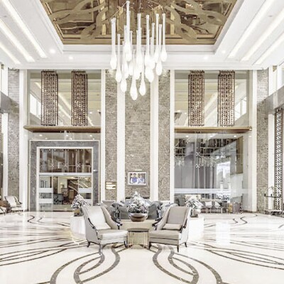 Case study: A modern Indian hotel lobby with seating areas, a marble reception desk, high ceilings, and hanging lights