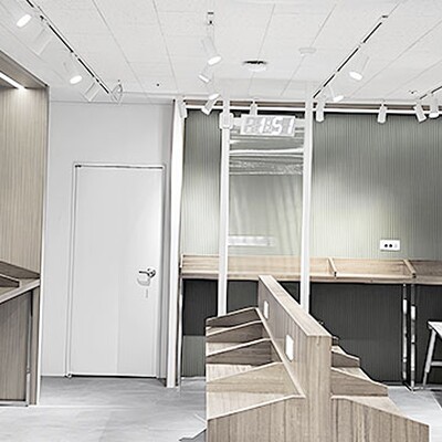 Modern study area with wooden carrel desks against olive green corrugated walls under bright track lighting.