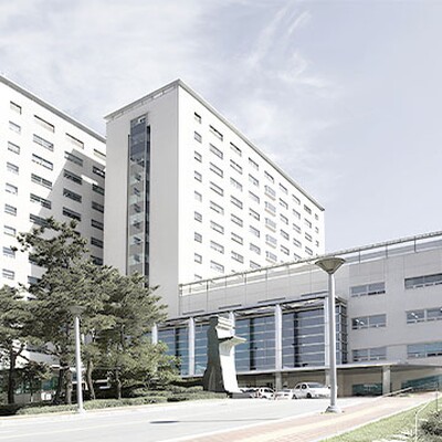 Large modern white university building with multiple wings and glass entrances under a bright blue sky in South Korea.