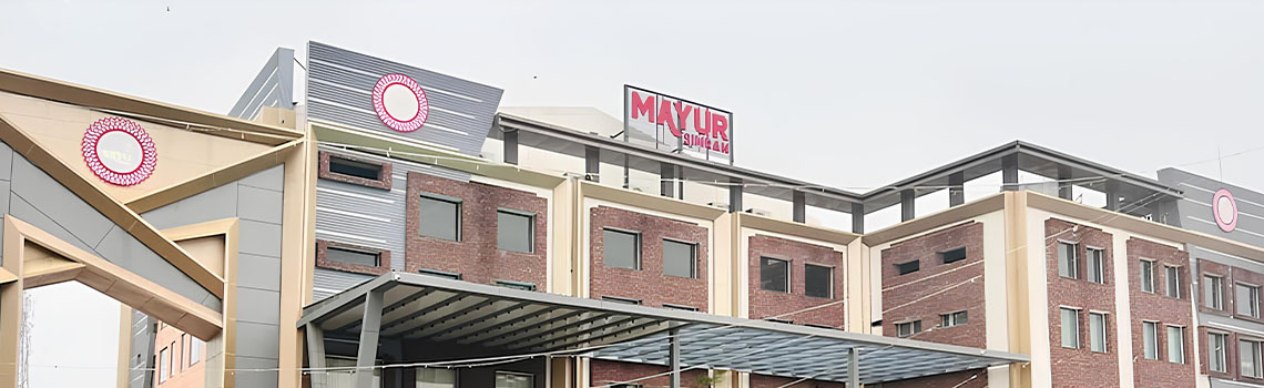 Modern multi-story hotel building with brick and white facade featuring a large MAYUR SIMRAN sign on the roof.