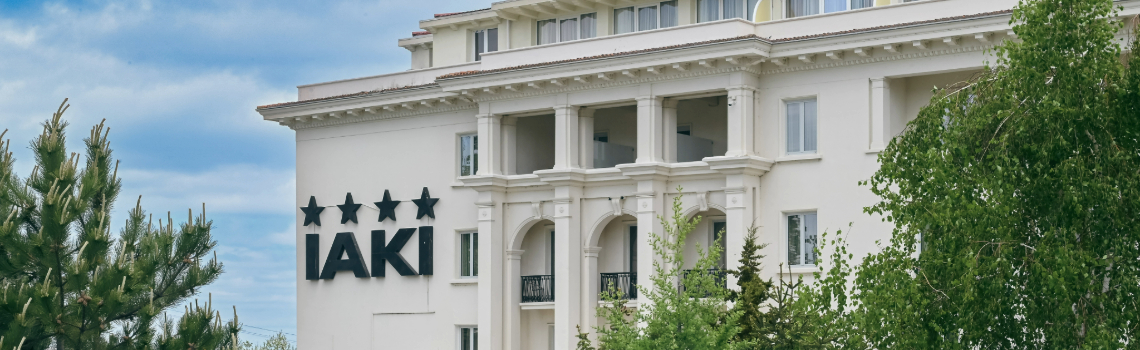 IAKI Conference & Spa Hotel exterior view with classic architecture and four-star sign, surrounded by lush green trees in Mamaia.