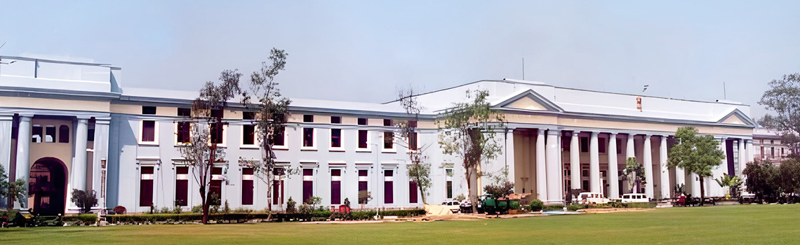 Elegant neoclassical building with large columns, pale blue facade, surrounded by green lawns and trees, exuding grandeur and calm.