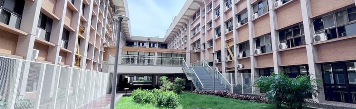 Providence University academic building featuring a modern sky bridge and lush greenery under a bright, clear blue sky.