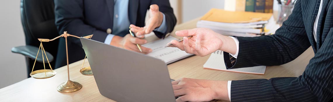 Case study: Lawyers at a desk with a laptop and scales of justice, featuring Zyxel Networks Nebula solution for a law firm.