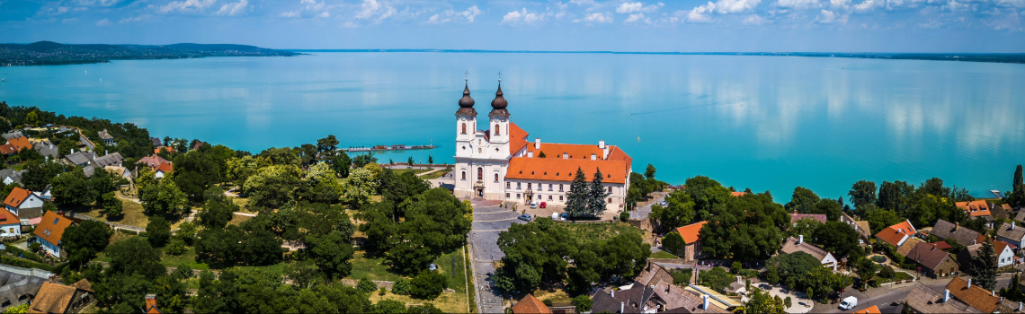 Spacious modern concert hall with red ceiling panels, tiered seating, wooden acoustic design, and a brightly lit stage prepared for performance.
