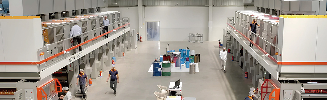 Workers operate large-scale printing and packaging machines inside a modern India Printing & Packaging factory  