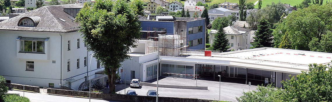 Valposchiavo Health Center in Switzerland surrounded by greenery, showcasing its multi-building healthcare facility.